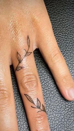 a woman's hand with a small tattoo on the middle finger and an arrow