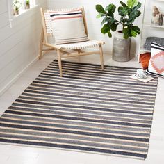 a striped rug with a chair and potted plant