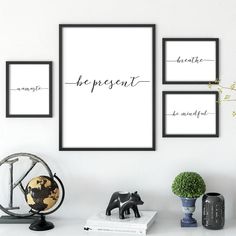 three black and white framed art prints on a wall above a desk with a globe