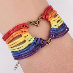 a woman's arm wearing a multicolored bracelet with gold heart clasps