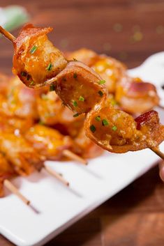 the skewers are covered with bacon and other toppings on a white plate