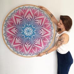 a woman standing next to a large circular artwork