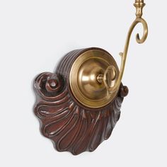 an ornately designed wall mounted hook on the side of a white wall with a gold - plated handle