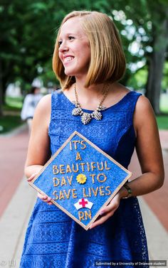 a woman in a blue dress holding a plaque that says it's a beautiful day to save lives