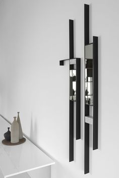 two black and white mirrors mounted to the side of a wall next to a vase