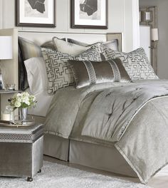 a bed with silver sheets and pillows on top of it next to a night stand