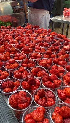 strawberries are arranged in plastic cups on a table