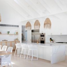 an open kitchen with white cabinets and counter tops is pictured in this image, there are several chairs around the table