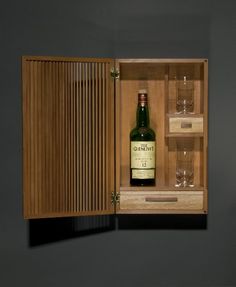 a bottle of wine in a wooden box with two glasses on the bottom and one empty glass next to it