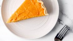 a piece of pie on a white plate next to a fork