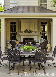 an outdoor dining area with chairs, table and fireplace