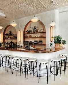 a bar with several stools and shelves filled with bottles