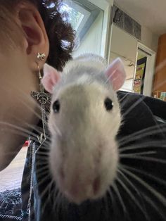 a woman is holding a rat in her lap and it's face up to the camera