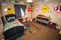 a child's bedroom with various traffic signs on the wall and carpeted floor