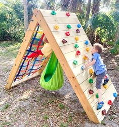 a young boy climbing up the side of a wooden climbing wall with plastic toys on it