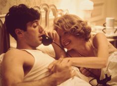 a man and woman laying in bed talking on the telephone