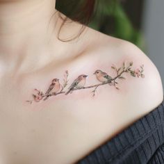 three birds sitting on a branch tattoo on the upper arm and shoulder, with pink flowers