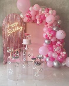 a pink birthday party with balloons, cake and confetti on the table in front of it