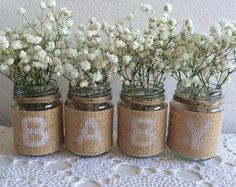 four mason jars with white flowers in them