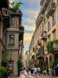 people are walking down the street in an old european city with tall buildings and balconies