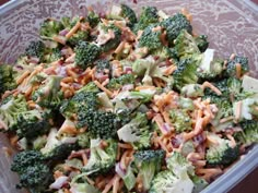 a plastic container filled with broccoli and other food on top of a table