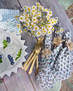 flowers and napkins are sitting on the table next to plates with utensils