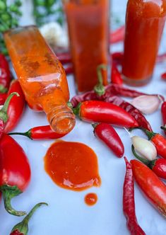 several bottles of sauce and peppers on a table