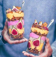 two people holding glasses filled with food and fruit on top of each other in their hands