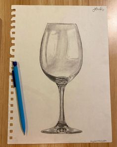 a pencil drawing of a wine glass sitting on top of a table next to a blue pen