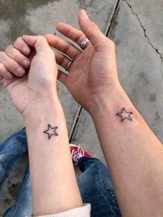 two people holding hands with small tattoos on their wrist and one has a star tattoo on it