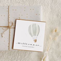 a card with a hot air balloon on it next to a gift box and twine