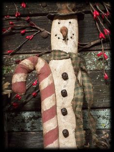 a snowman made out of wood with a candy cane