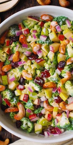 a bowl filled with broccoli, apples, raisins and cranberries