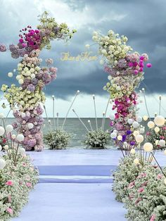 an outdoor wedding ceremony with flowers on the aisle and clouds in the sky behind it