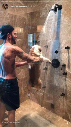 a man is taking a shower with an animal in it's hand and holding the shower head