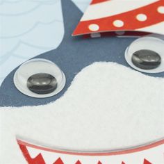 a close up of a paper cut out of a shark with two buttons on it