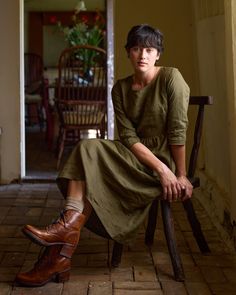 a woman sitting in a chair with her legs crossed and wearing brown shoes, looking off to the side