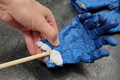 a person wearing blue gloves and holding a toothbrush in their left hand while cleaning something on the ground