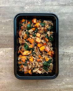 a black container filled with food on top of a wooden table