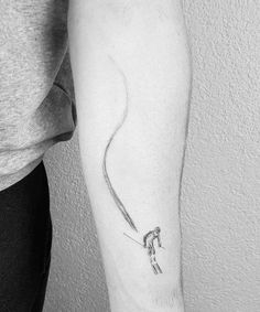 a person with a tattoo on their arm holding onto a string that is attached to the wrist