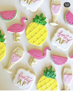 some decorated cookies are sitting on a white surface with pineapples and watermelon