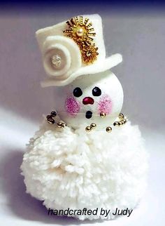 a small white snowman wearing a top hat and pearls on it's head