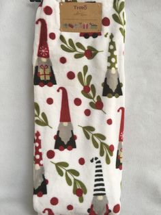 an oven mitt with gnomes and holly leaves on it, hanging from a hook