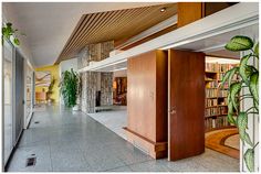 an open door leading to a library with bookshelves and plants on the wall