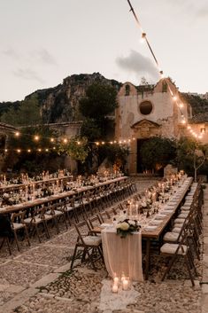 an outdoor dining area with long tables and chairs set up for a formal function in the evening