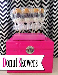 donut skewers are stacked on top of a pink box