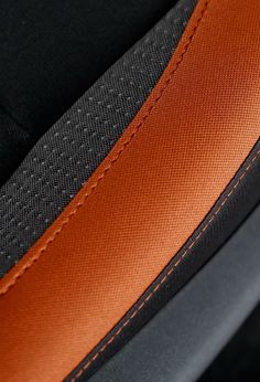 an orange and black leather seat cover with stitching on the bottom half of it