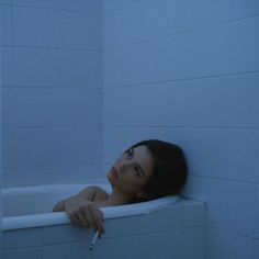 a woman leaning on the edge of a bathtub with her hand resting on the edge