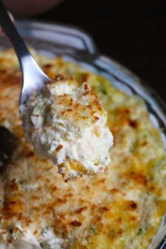 a spoon with some food in it on a glass plate and someone is holding something up to the camera