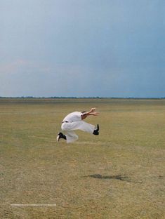 a man is jumping in the air to catch a frisbee on an open field